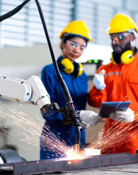 Two people in hard hats and goggles working on a machine.