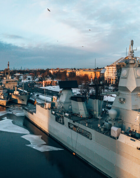 A group of ships in the water near some buildings.