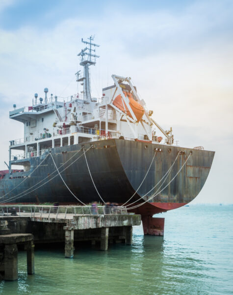 A large ship docked in the ocean next to a pier.