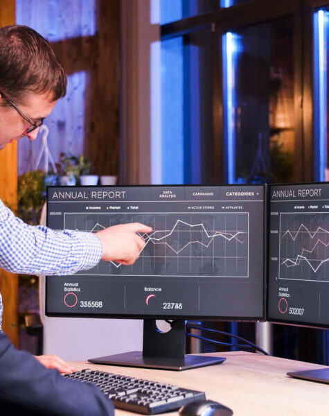 A man is sitting at his desk with two monitors.